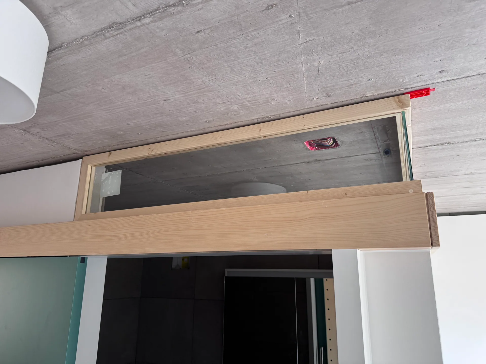 Verglastes Oblicht mit Holzrahmen über einer Tür